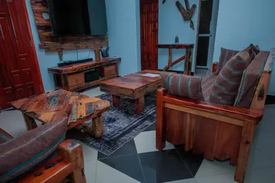 a living room with wooden furniture and a flat screen tv at Mati Residence Ngarenaro in Babati