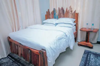 a bed with a wooden headboard in a bedroom at Mati Residence Ngarenaro in Babati
