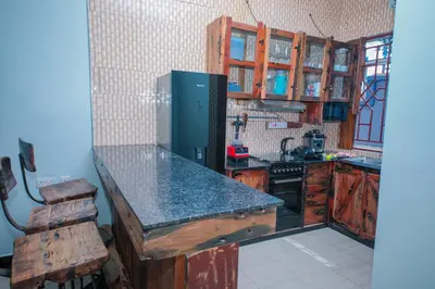 a kitchen with a black counter top and a refrigerator at Mati Residence Ngarenaro in Babati