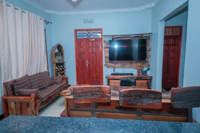 a living room with a tv and a couch and chairs at Mati Residence Ngarenaro in Babati