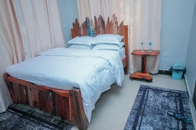 a bedroom with a large bed with a wooden headboard at Mati Residence Ngarenaro in Babati