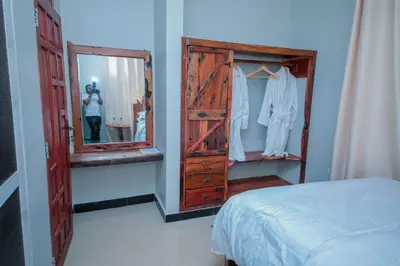 a person taking a picture of a dresser in a bedroom at Mati Residence Ngarenaro in Babati