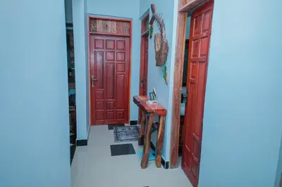 a hallway with two red doors and a wooden stool at Mati Residence Ngarenaro in Babati
