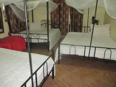 a bedroom with three beds with white sheets at Fanaka Safaris Campsite & Lodges in Mto wa Mbu