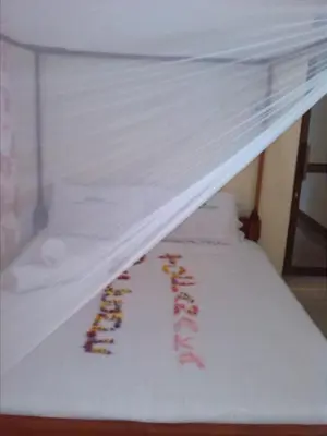 a bunk bed with a white bedsheet and a ladder at Fanaka Safaris Campsite & Lodges in Mto wa Mbu