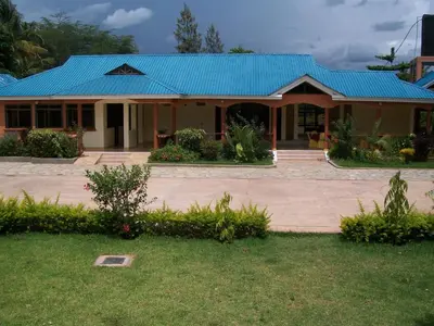 a house with a blue roof and a yard at Fanaka Safaris Campsite & Lodges in Mto wa Mbu