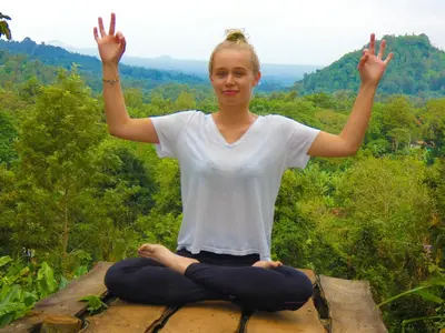 a woman is sitting in a yoga pose on a rock at Makini Swing Adventure in Arusha