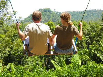 a couple riding on a zip line through the trees at Makini Swing Adventure in Arusha
