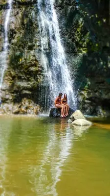 a couple sitting on a rock in front of a waterfall at Makini Swing Adventure in Arusha