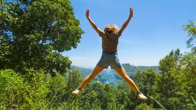 a woman jumping in the air with her arms in the air at Makini Swing Adventure in Arusha