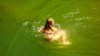 a woman swimming in a pool of green water at Makini Swing Adventure in Arusha