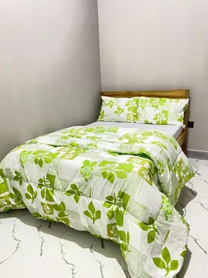 a bed with a green and white comforter and pillows at Stay with Rodjazz in Usa River