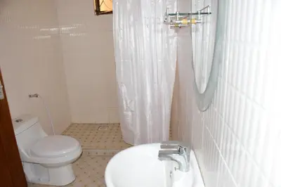 a white bathroom with a toilet and a sink at Hostel in Tengeru