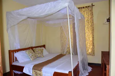 a bedroom with a canopy bed with white sheets and pillows at Hostel in Tengeru