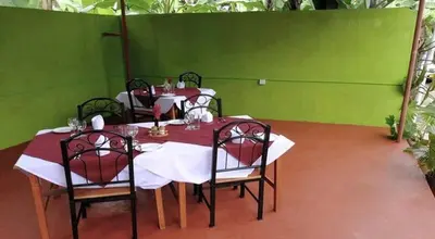 a dining room with three tables and chairs and green walls at Urafiki House in Arusha