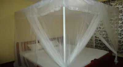 a canopy bed with white curtains in a bedroom at Urafiki House in Arusha