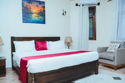 a bedroom with a large bed and a chair at SAS Residence in Arusha