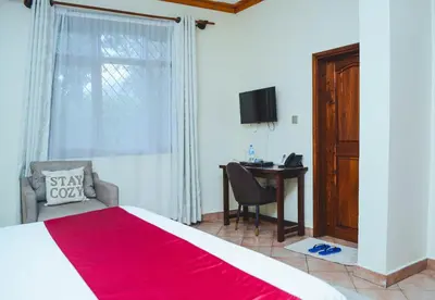 a bedroom with a bed and a desk and a window at SAS Residence in Arusha