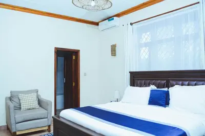 a bedroom with a bed and a chair at SAS Residence in Arusha