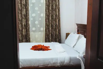 a white bed with a flower on top of it at SAS Residence in Arusha