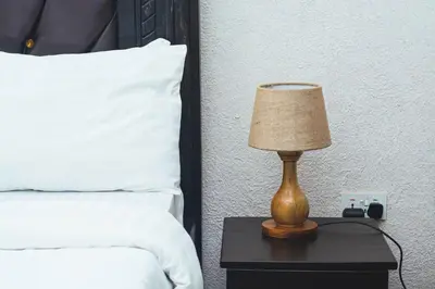 a lamp on a night stand next to a bed at SAS Residence in Arusha