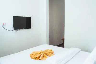 a room with a white bed and a tv on the wall at SAS Residence in Arusha