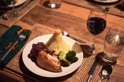 a plate of food on a table with a glass of wine at Hillside Retreat – Africa Amini Life in Usa River