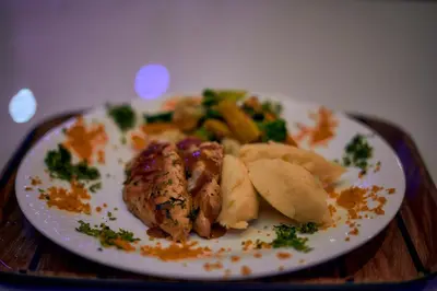 a plate of food with chicken and vegetables on a table at Orlando Cottages in Arusha