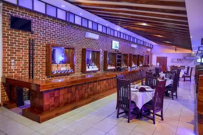 a restaurant with tables and chairs and a brick wall at Orlando Cottages in Arusha