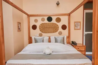 a bedroom with a large bed with a wooden headboard at Orlando Cottages in Arusha
