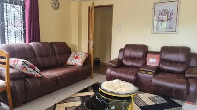 a living room with brown leather furniture and a couch at Space haven 02 in Arusha