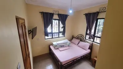 a small room with a bed and two windows at Space haven 02 in Arusha