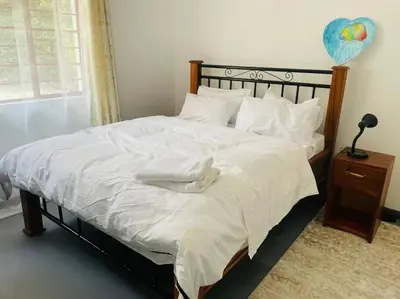 a bedroom with a large bed with white sheets at Bai-Mai Homes- Kijenge in Arusha