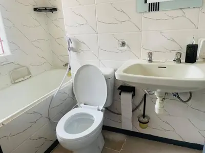 a white bathroom with a toilet and a sink at Bai-Mai Homes- Kijenge in Arusha
