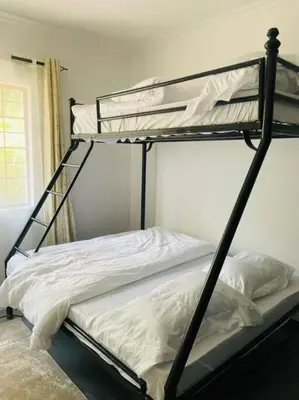 a bedroom with two bunk beds with white sheets at Bai-Mai Homes- Kijenge in Arusha