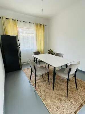 a dining room with a white table and chairs at Bai-Mai Homes- Kijenge in Arusha