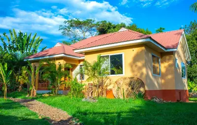 a small yellow house with a red roof at Msamaria Lori Hostel in Moshi