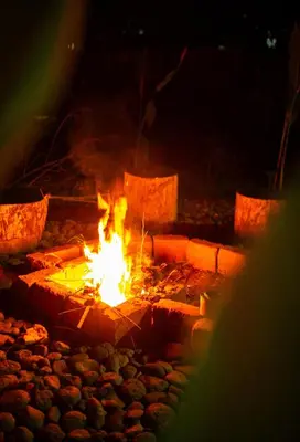 a fire burns in a fire pit at night at Msamaria Lori Hostel in Moshi
