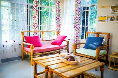 a room with two chairs and a table and windows at Msamaria Lori Hostel in Moshi