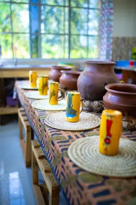a table topped with plates with cups on them at Msamaria Lori Hostel in Moshi