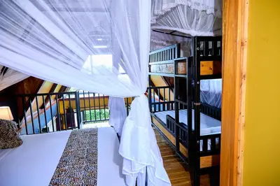 a room with a bed and bunk beds with a window at Shamba Lodge Cabin X in Arusha