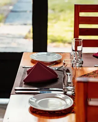 a wooden table with plates and glasses on it at Shamba Lodge Cabin X in Arusha
