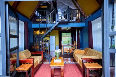 a living room with couches and tables and stairs at Shamba Lodge Cabin X in Arusha