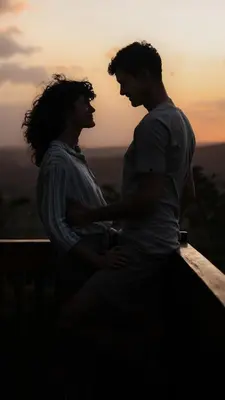 a man and a woman standing in front of the sunset at Shamba Lodge Cabin X in Arusha