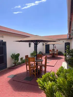 a patio with a table and chairs and an umbrella at Amora Homestay and Safaris in Karatu