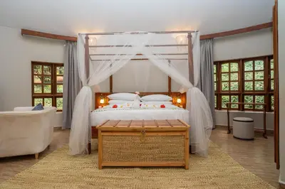 a bedroom with a canopy bed with a wooden table at Turaco Ngorongoro Valley, a Tribute Portfolio Lodge in Karatu