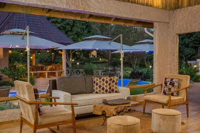 a patio with a couch and chairs and umbrellas at Turaco Ngorongoro Valley, a Tribute Portfolio Lodge in Karatu
