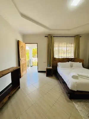 a bedroom with a large white bed and a door at Urban Nest in Arusha