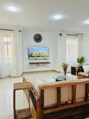 a living room with a table and a clock on the wall at Urban Nest in Arusha