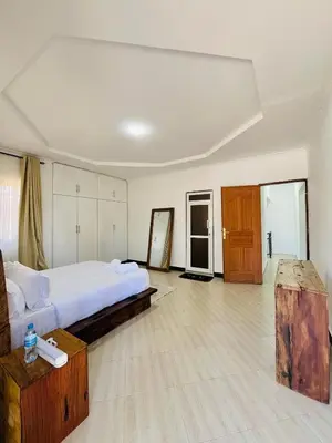 a large bedroom with a bed and a wooden table at Urban Nest in Arusha